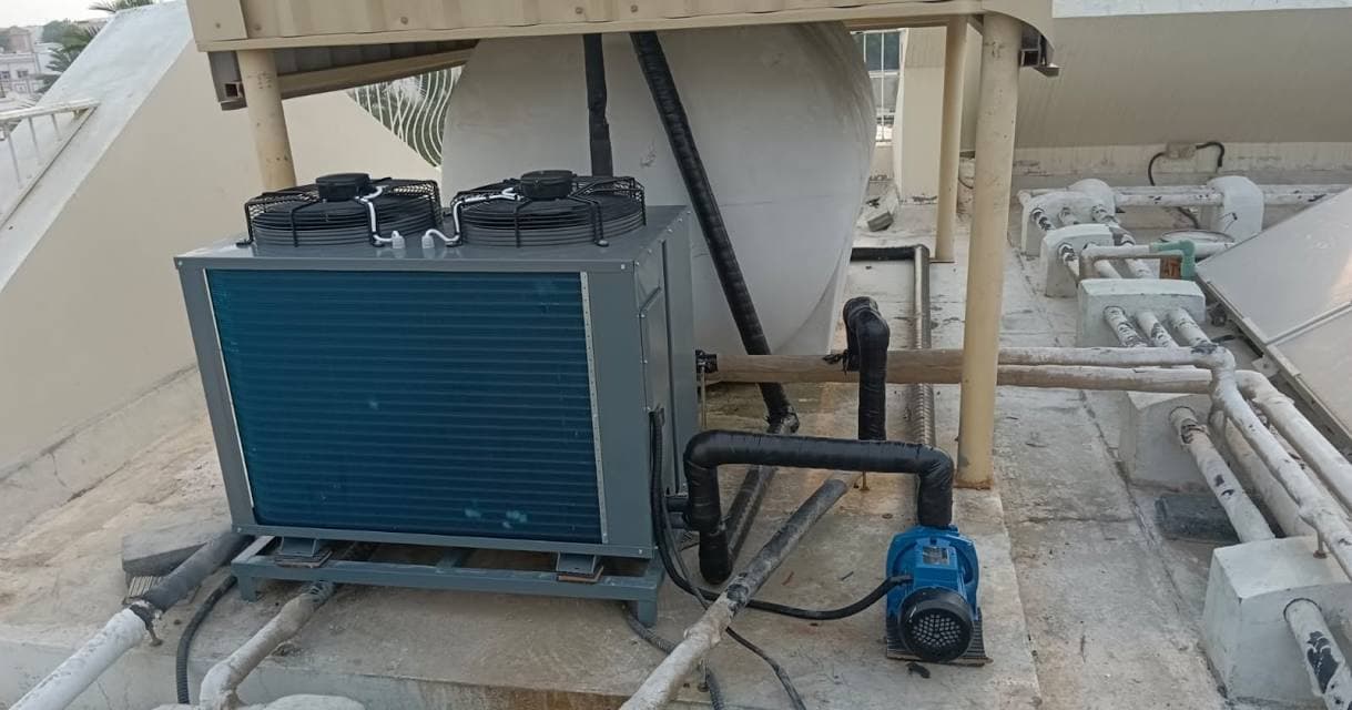 Air-cooled chiller unit with pool pump installed and running on a Dubai rooftop, connected to insulated piping